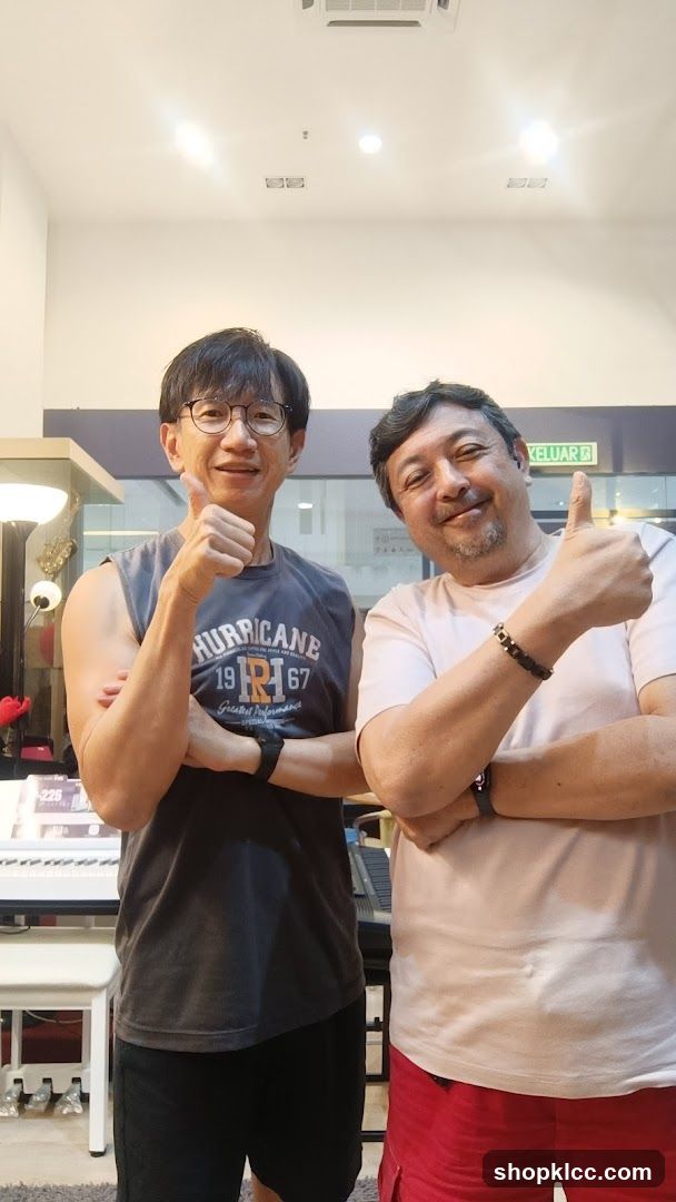 Two men giving thumbs up in a music shop interior