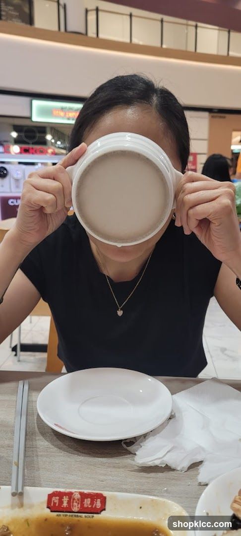 Person drinking soup in a mall food court