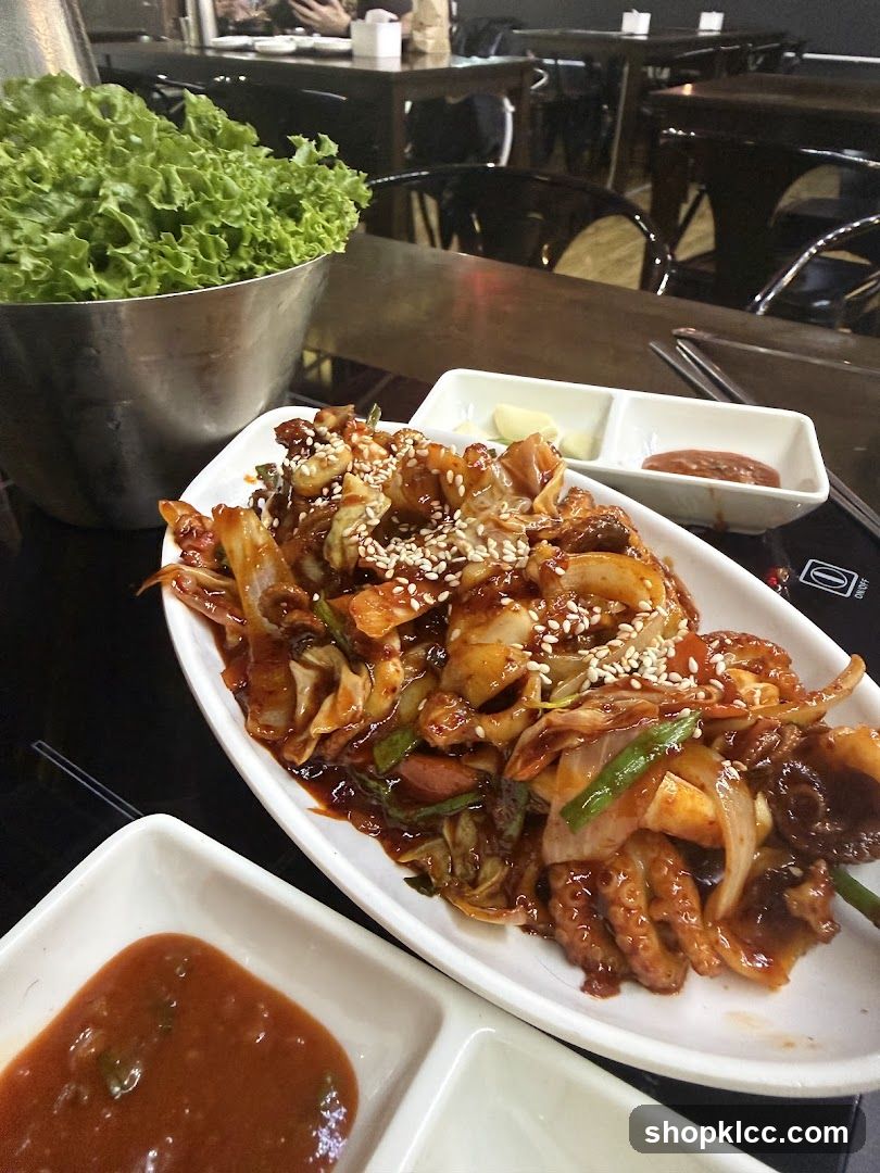 Korean-style stir-fried seafood dish with dipping sauces and lettuce