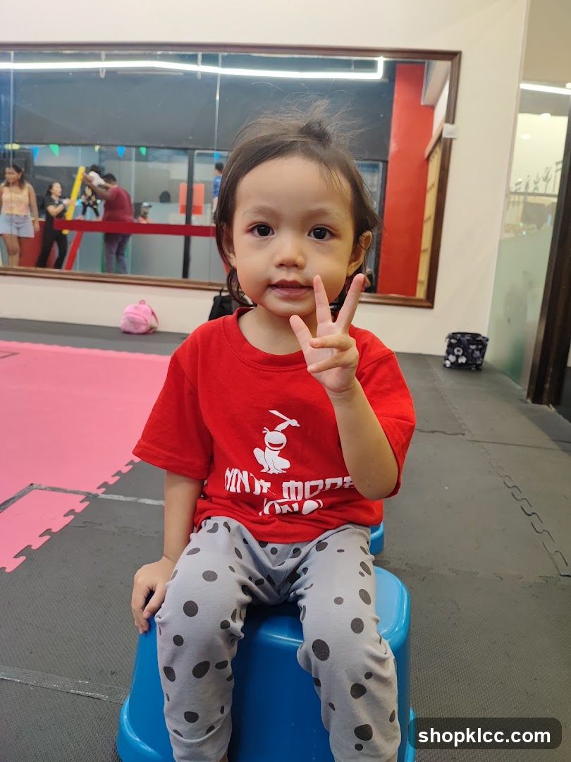 Child in a red shirt and polka dot pants making a peace sign