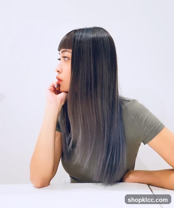 Woman with long dark hair and bangs sitting at a table