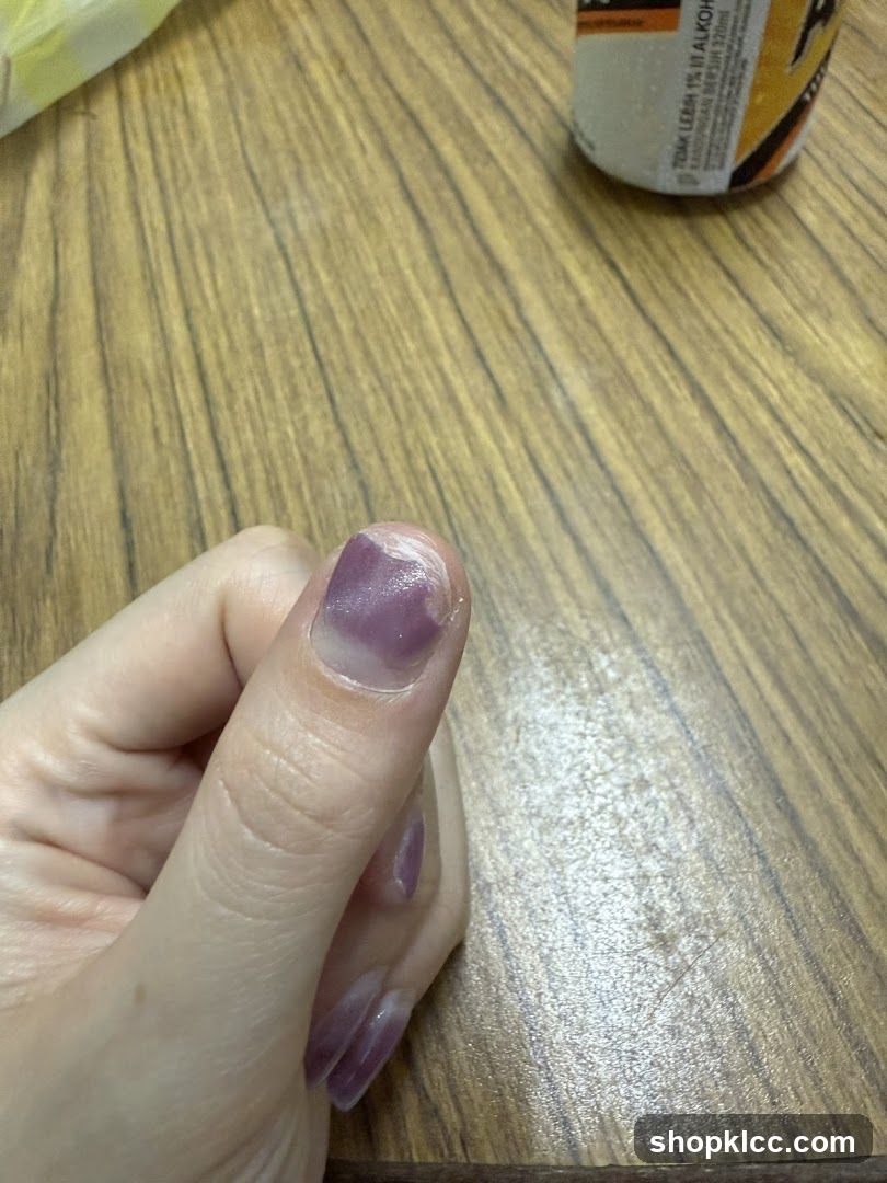 Hand with purple nail polish on wooden table