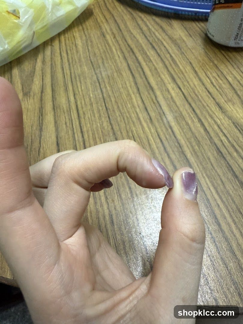 Hand with purple nail polish on wooden table