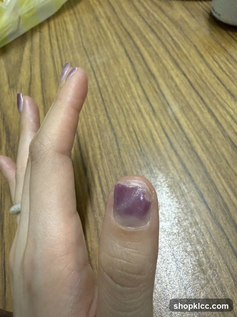 Hand with purple nail polish on wooden table