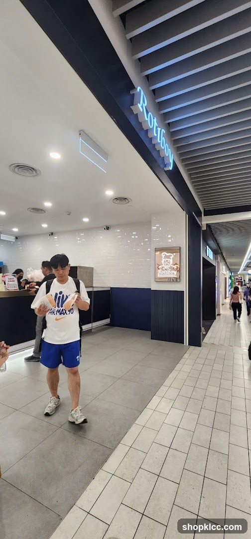 Person in mall corridor near Rottey shop