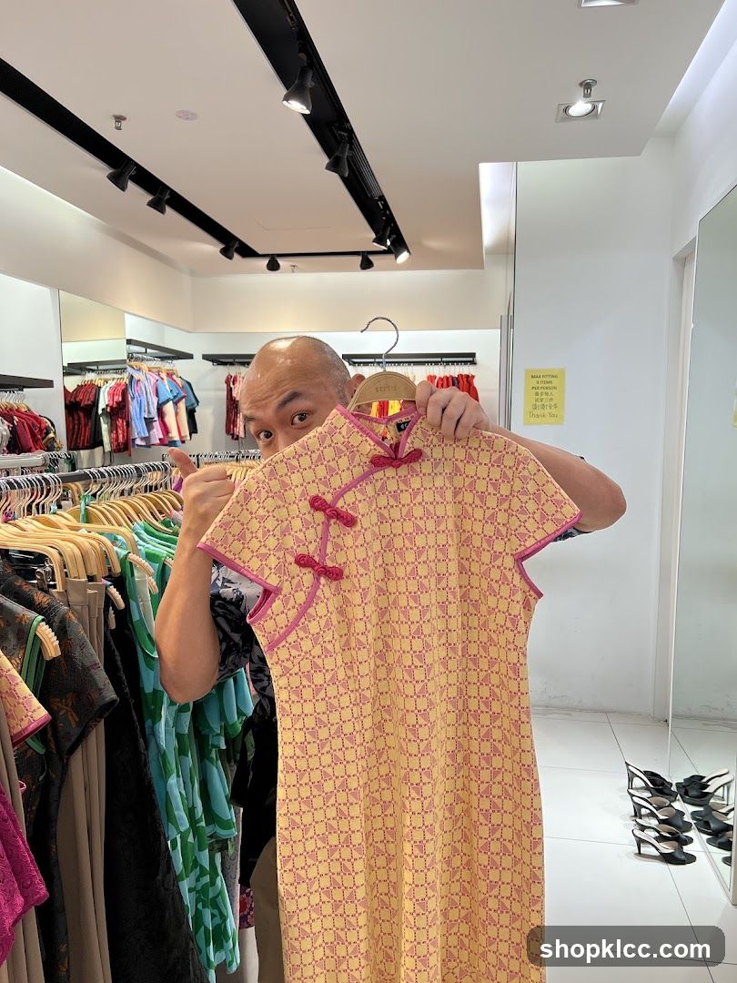 Man holding yellow patterned dress in clothing store