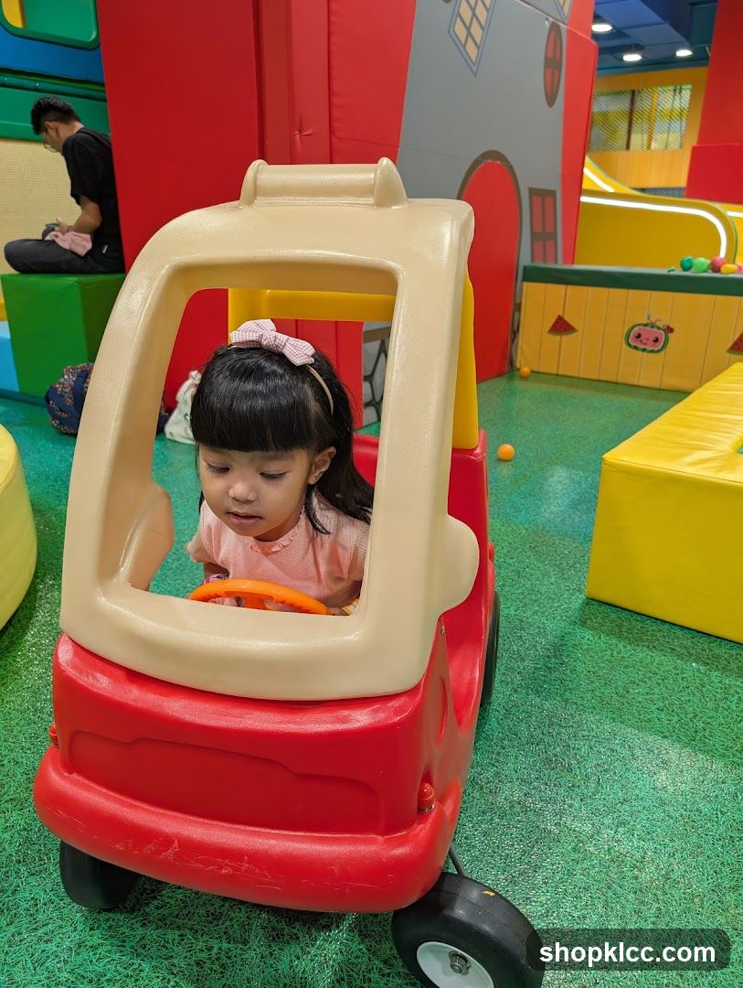 Child in toy car at indoor play area