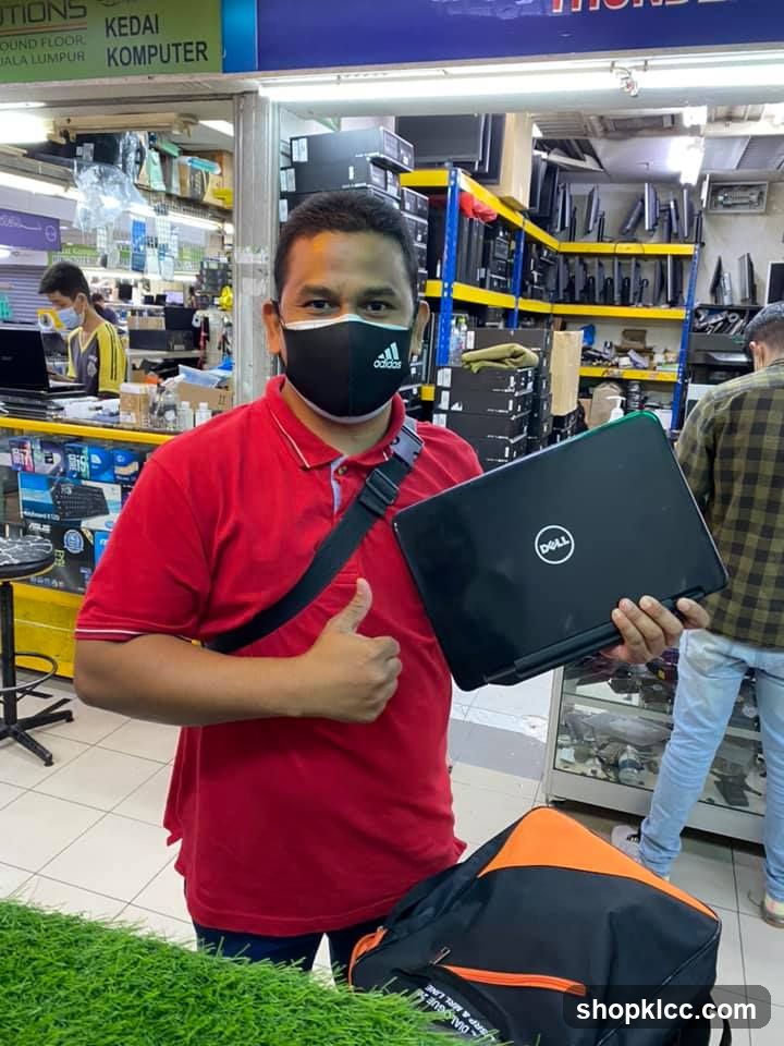 Man holding laptop in electronics shop