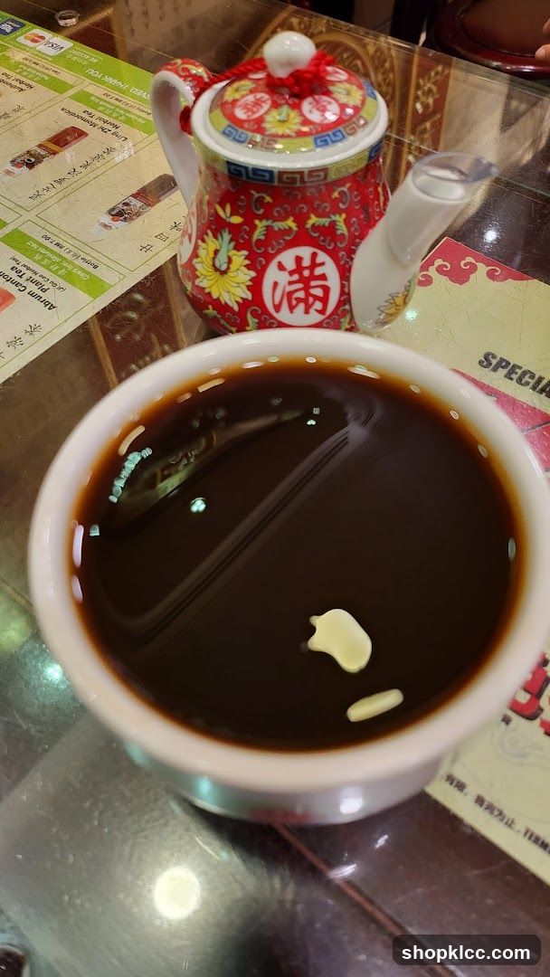 Bowl of dark liquid with garnish and decorative teapot