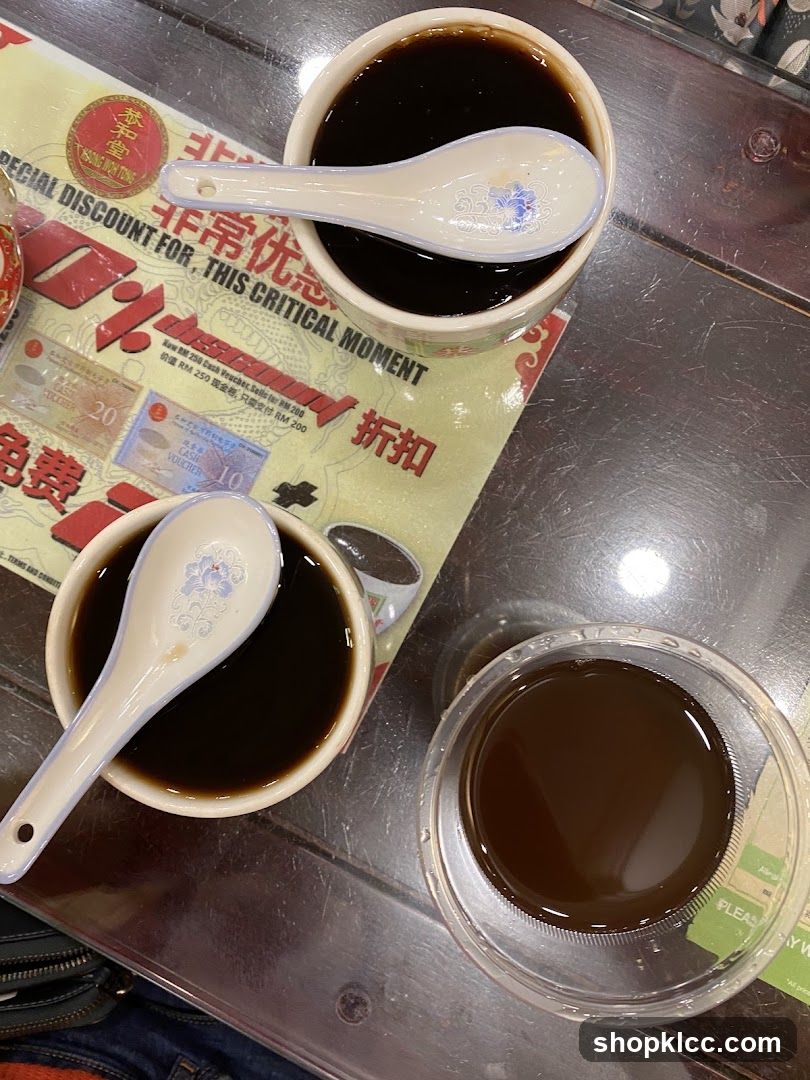 Bowl of dark liquid with spoons and a plastic cup on metal table