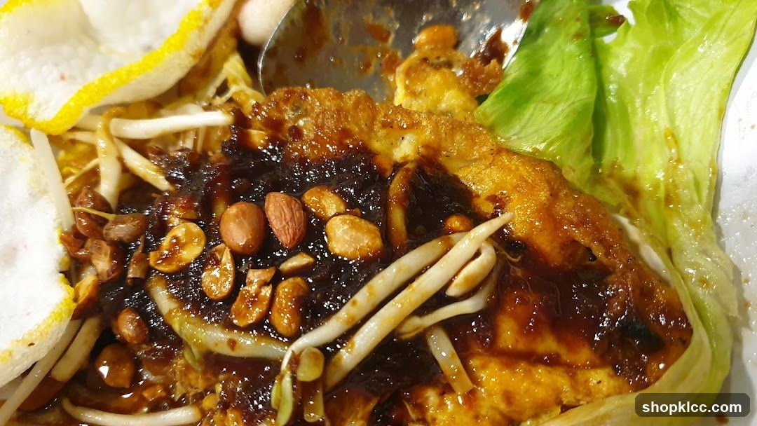 Close-up of a dish with fried tofu, bean sprouts, peanuts, and crackers.