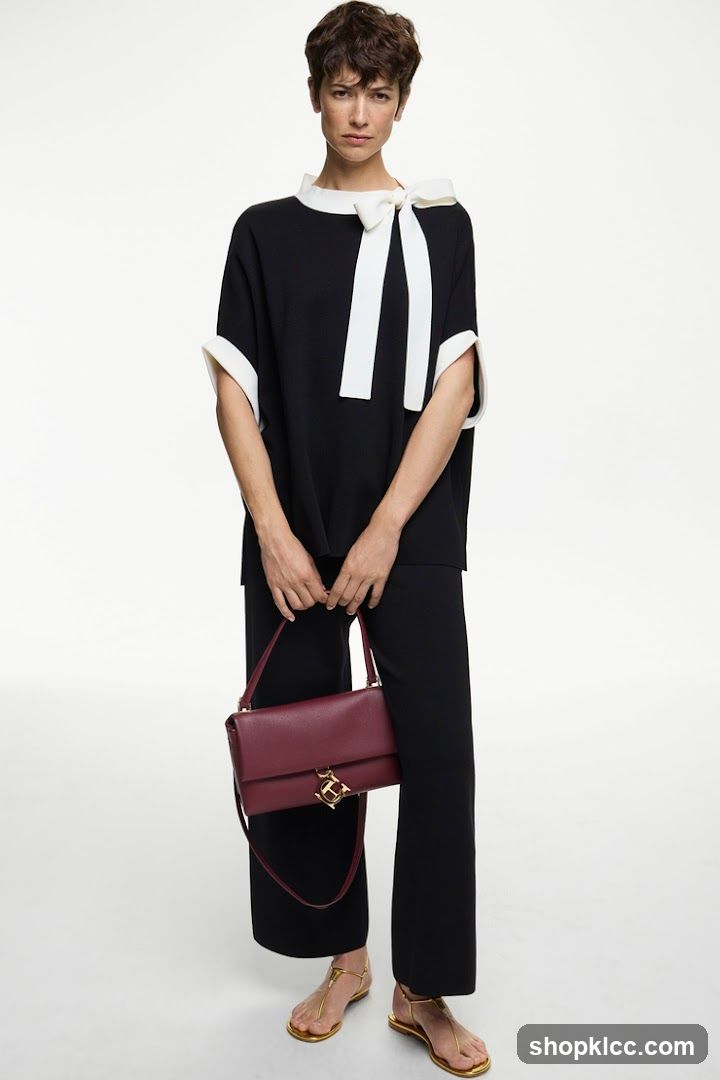 Model wearing black and white outfit with burgundy handbag