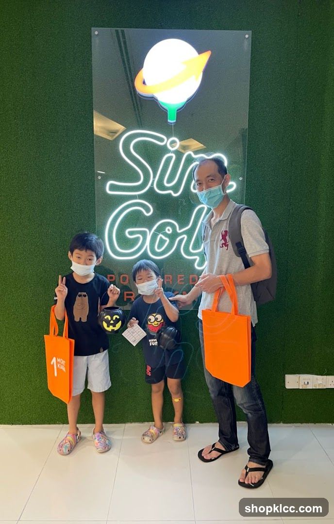 Family with orange bags in front of neon sign