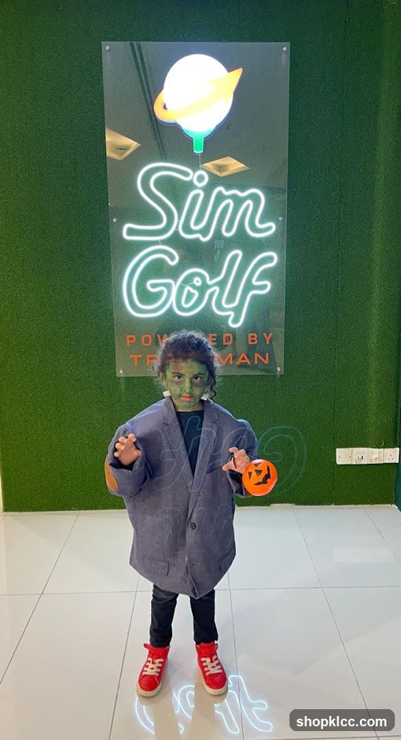 Child in costume posing with Sim Golf sign