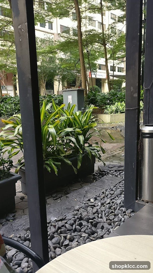 Outdoor seating area with plants and buildings in background