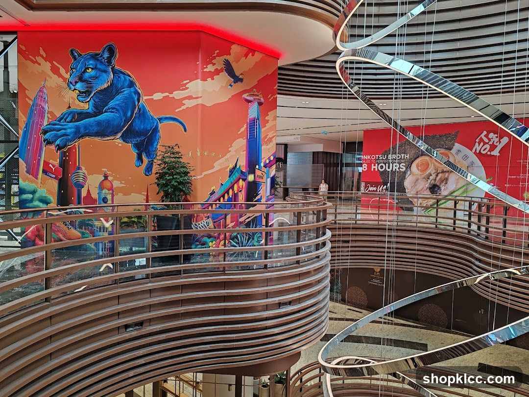 Interior of a modern shopping mall with vibrant murals and a large chandelier.