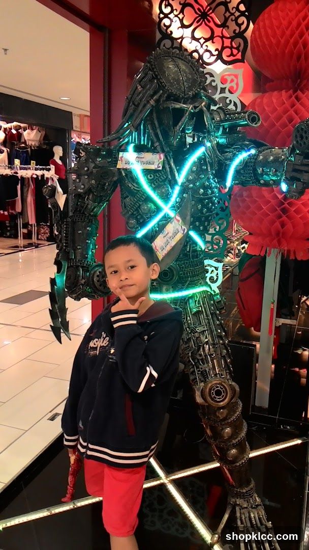 Boy Poses Next to Predator Statue