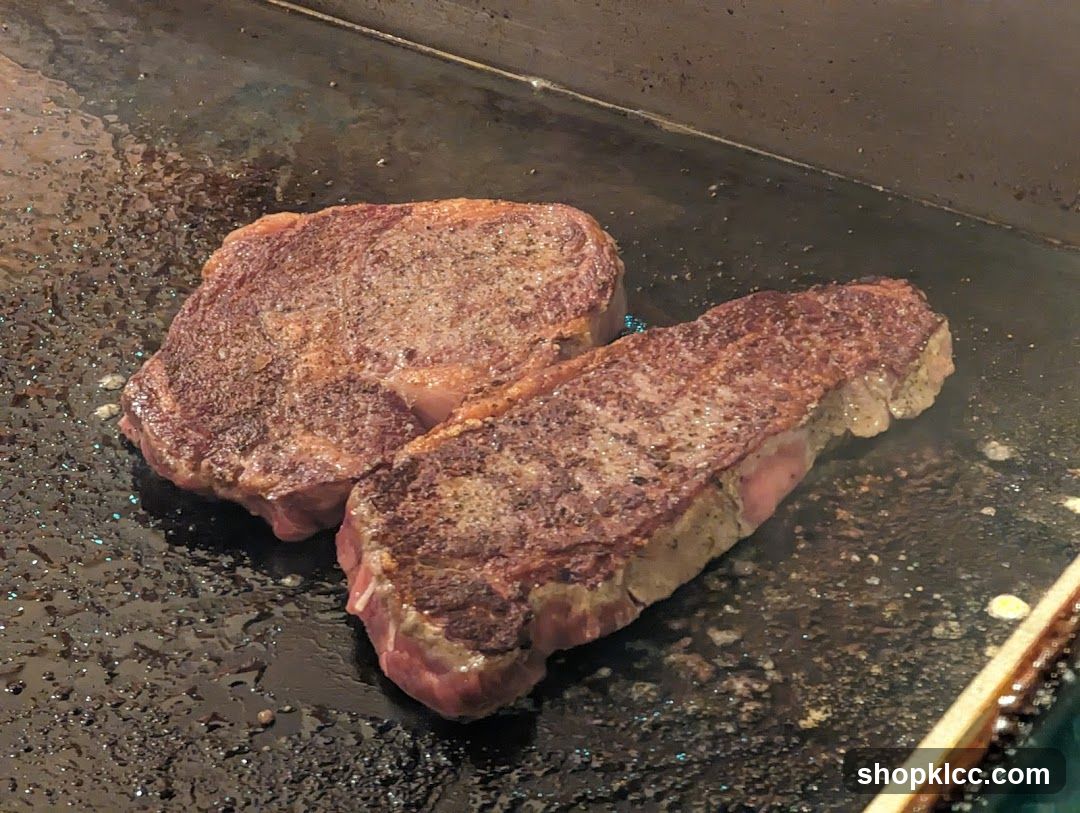 Two steaks cooking on a griddle