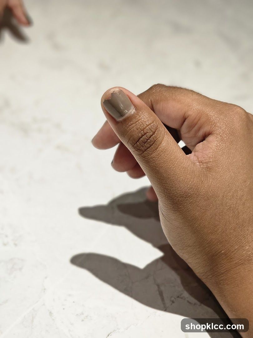 Hand with painted nails on marble surface
