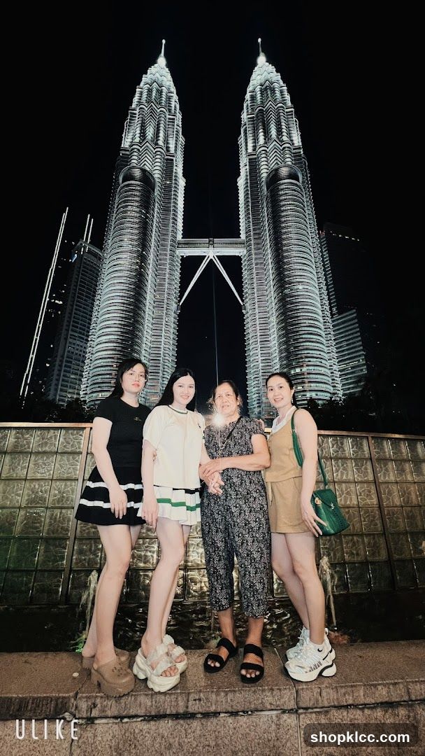Four people posing in front of the Petronas Towers at night