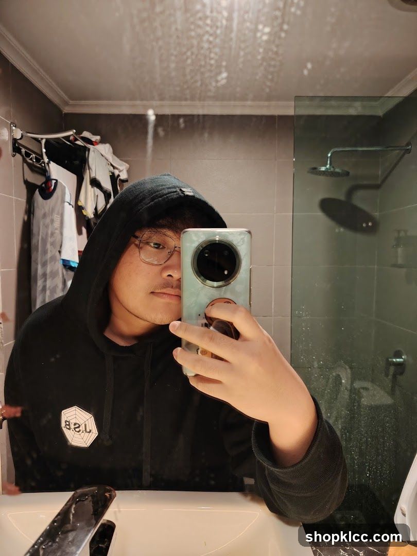 Man in Hoodie Taking Mirror Selfie in Bathroom