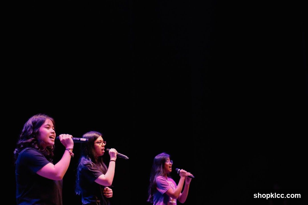 Three girls singing into microphones on stage