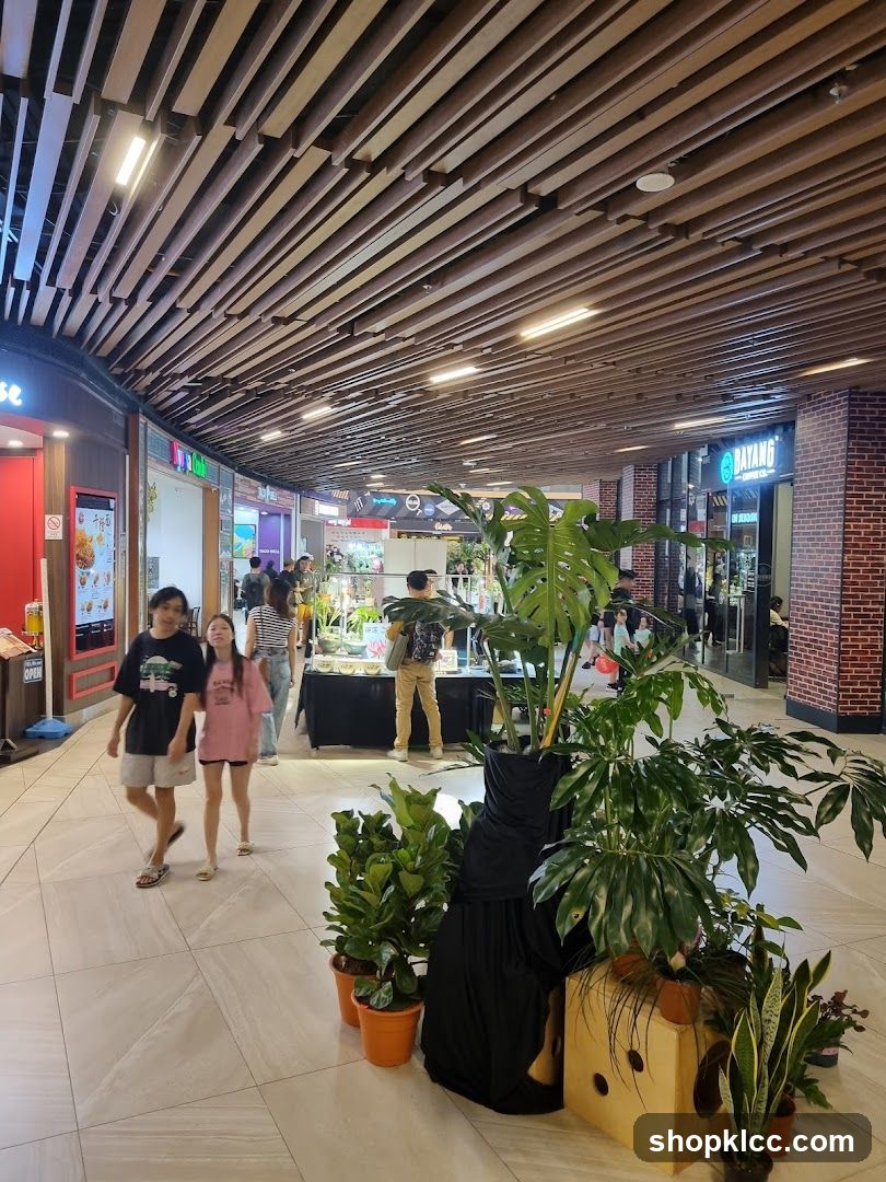 Indoor shopping mall walkway with plants and shops