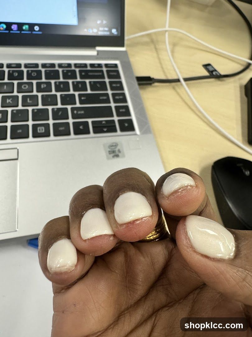 Hand with white nail polish near laptop