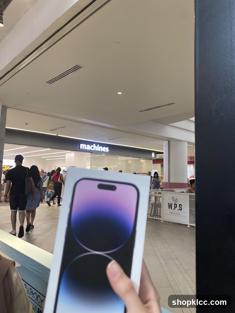 Person holding a new iPhone box in front of a store