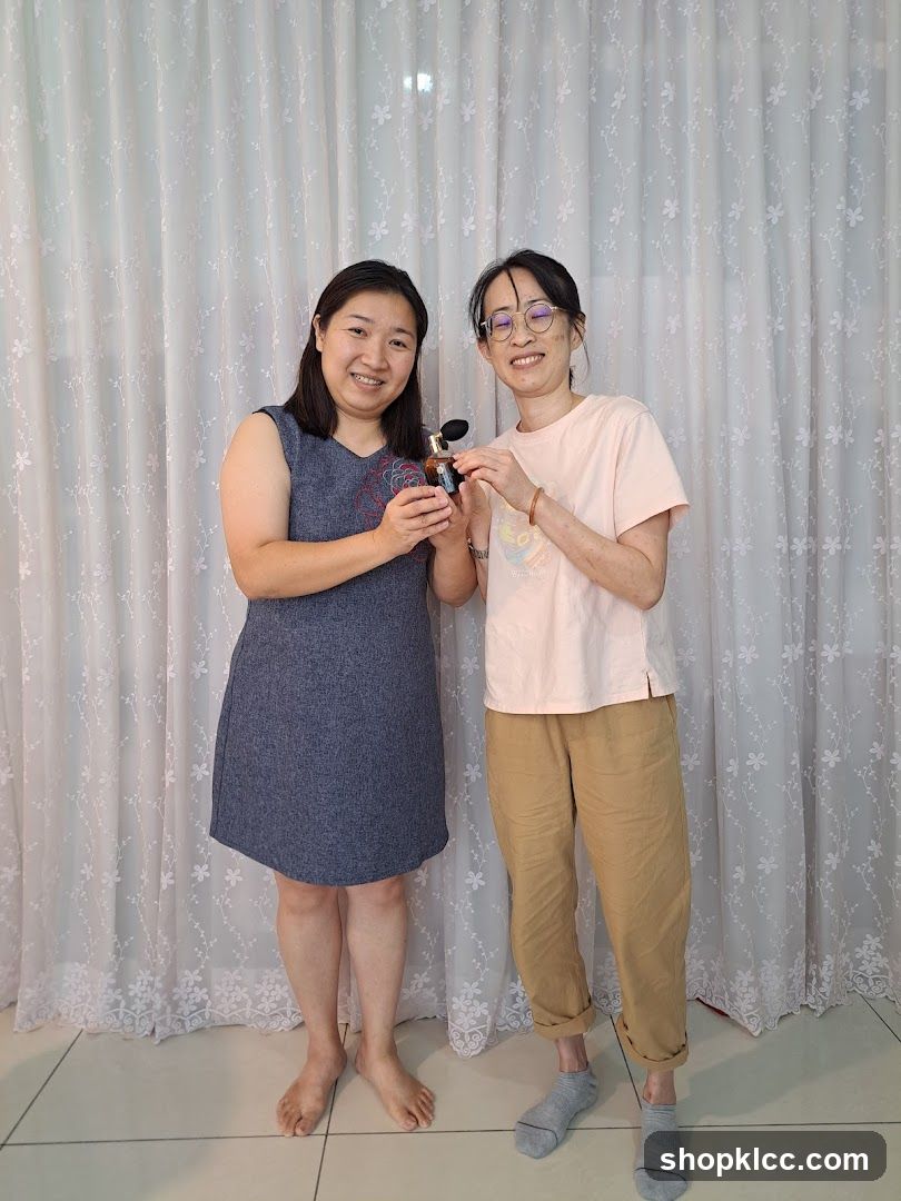 Two women holding a perfume bottle