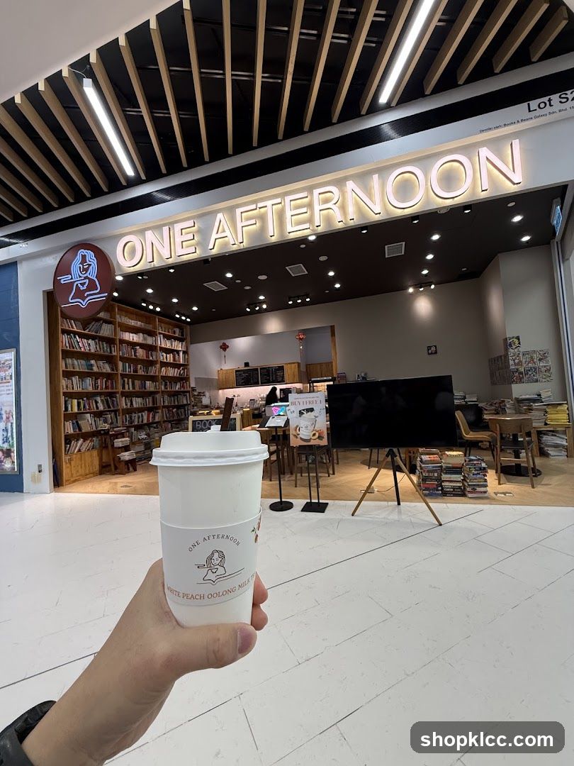 A hand holding a cup in front of a bookstore cafe
