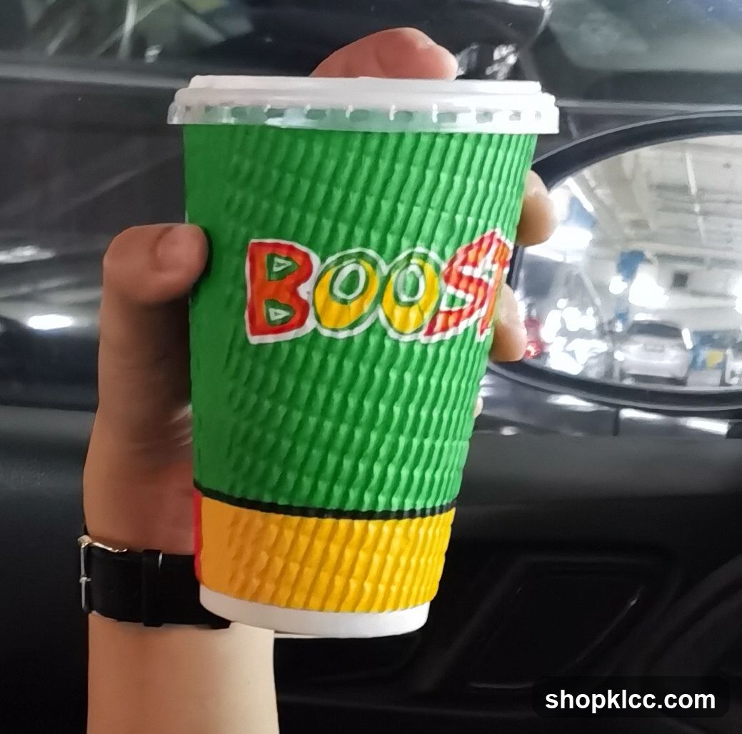 Hand holding a green and yellow cup with 'BOOST' logo