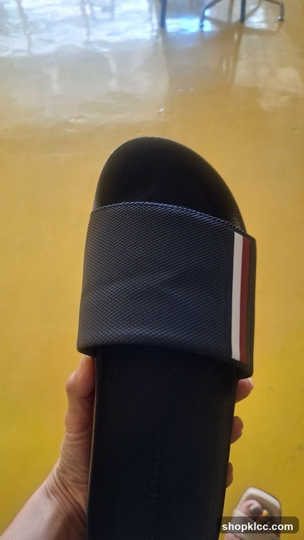 Hand holding a black slide sandal