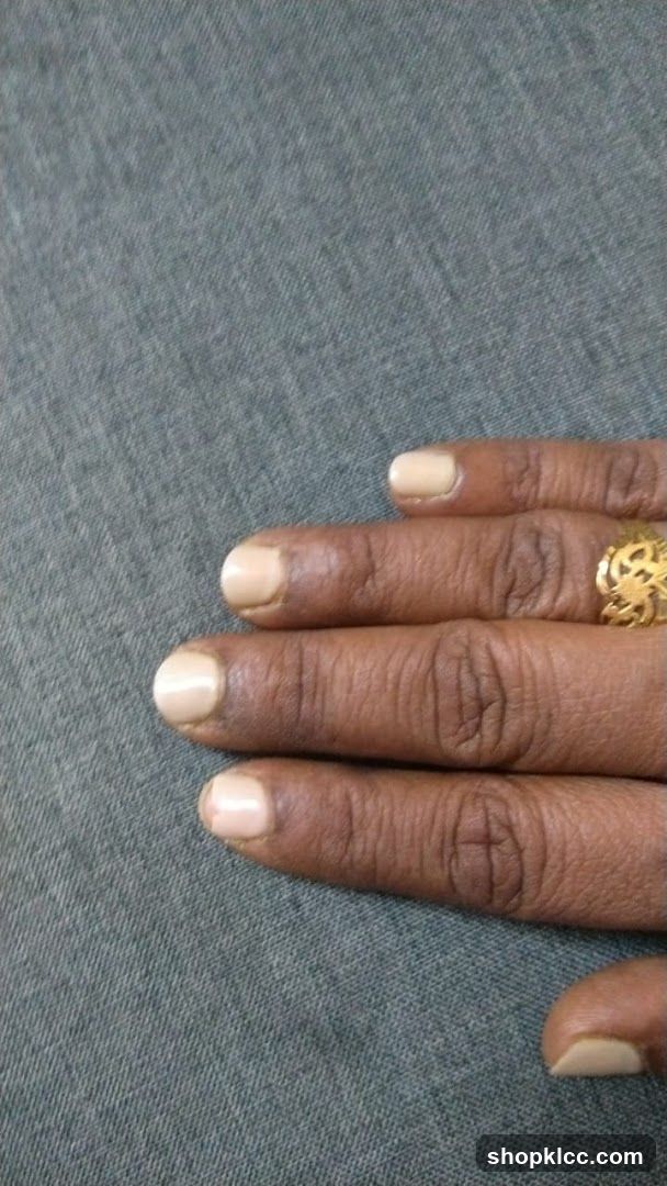 Fingers with light-colored nail polish and a gold ring