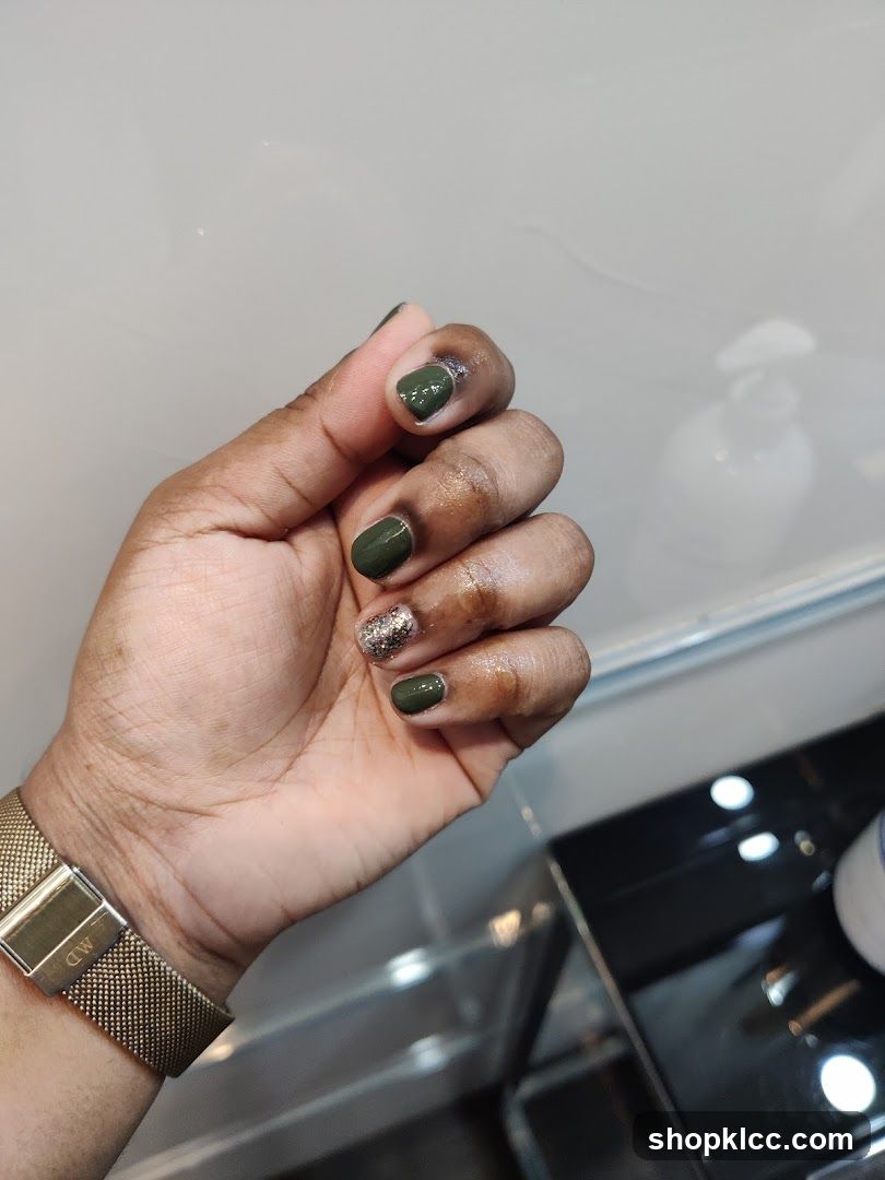Hand with green and glitter nail polish