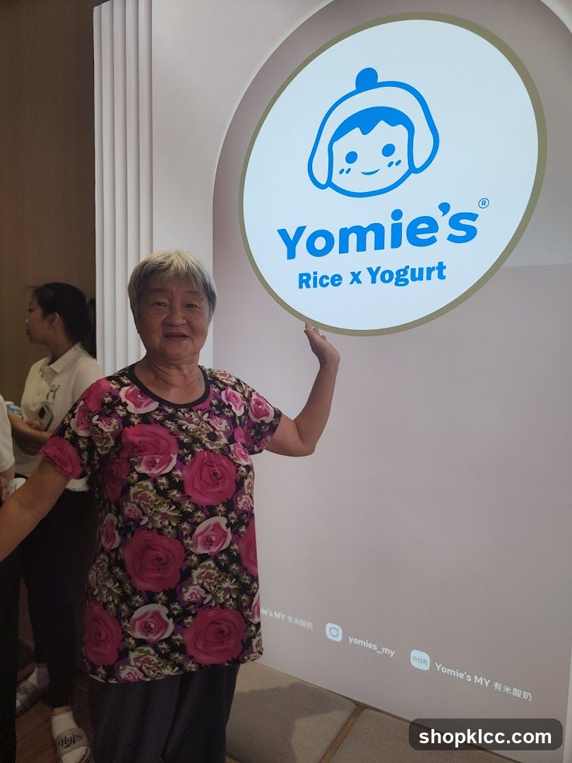 Woman Poses Next to Yomie's Logo