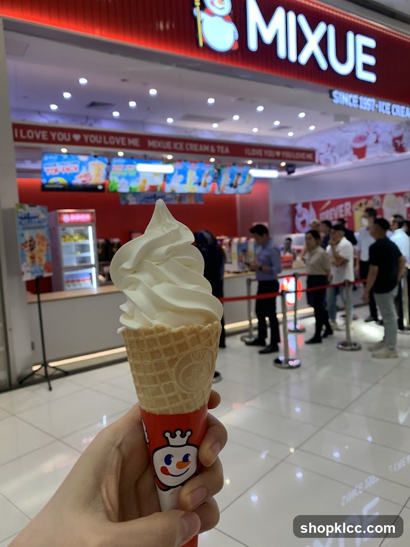Person holding an ice cream cone in front of a MIXUE store