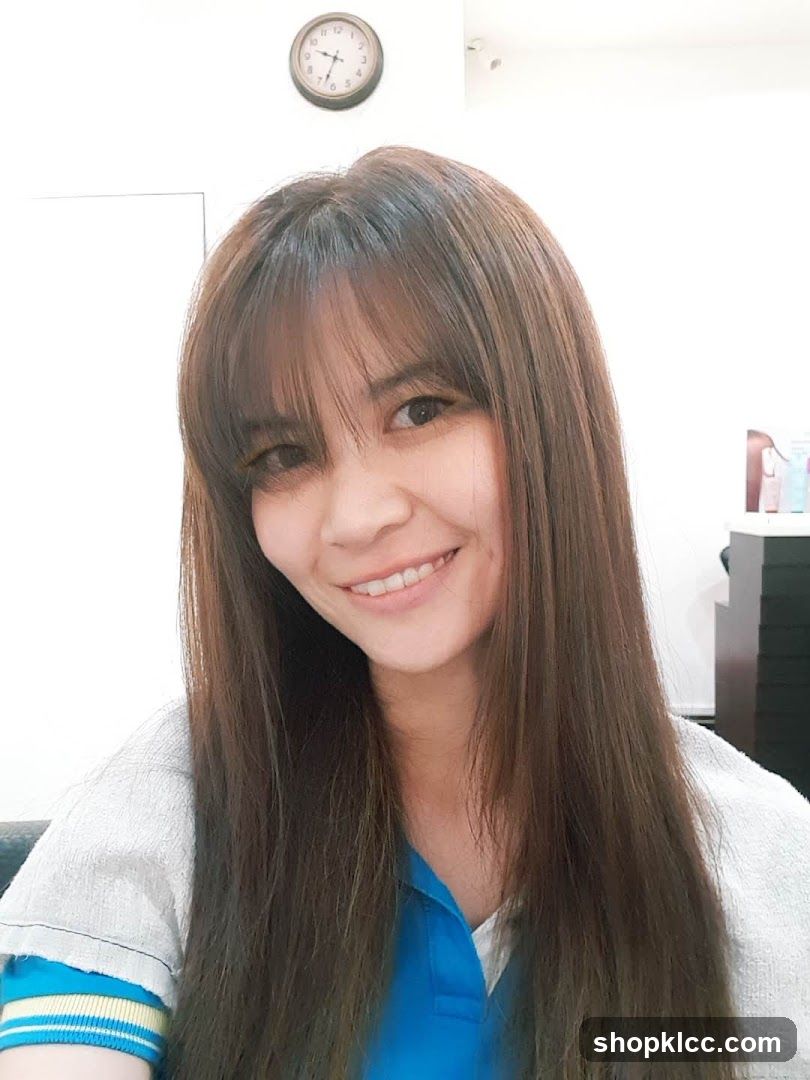 Portrait of a woman with long brown hair and bangs, smiling at the camera.