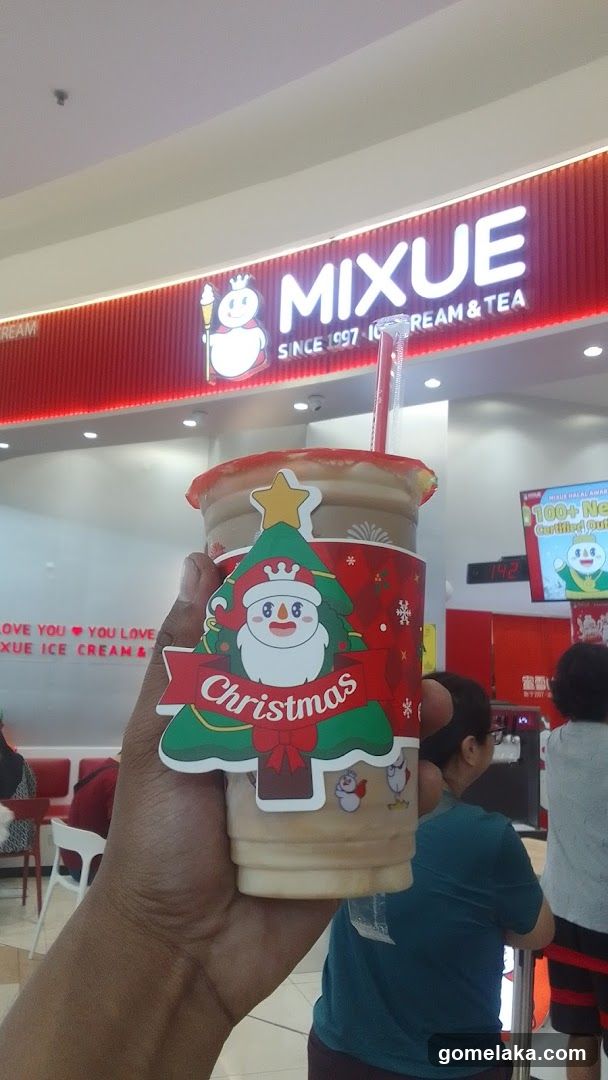 Hand holding Christmas-themed drink at Mixue store