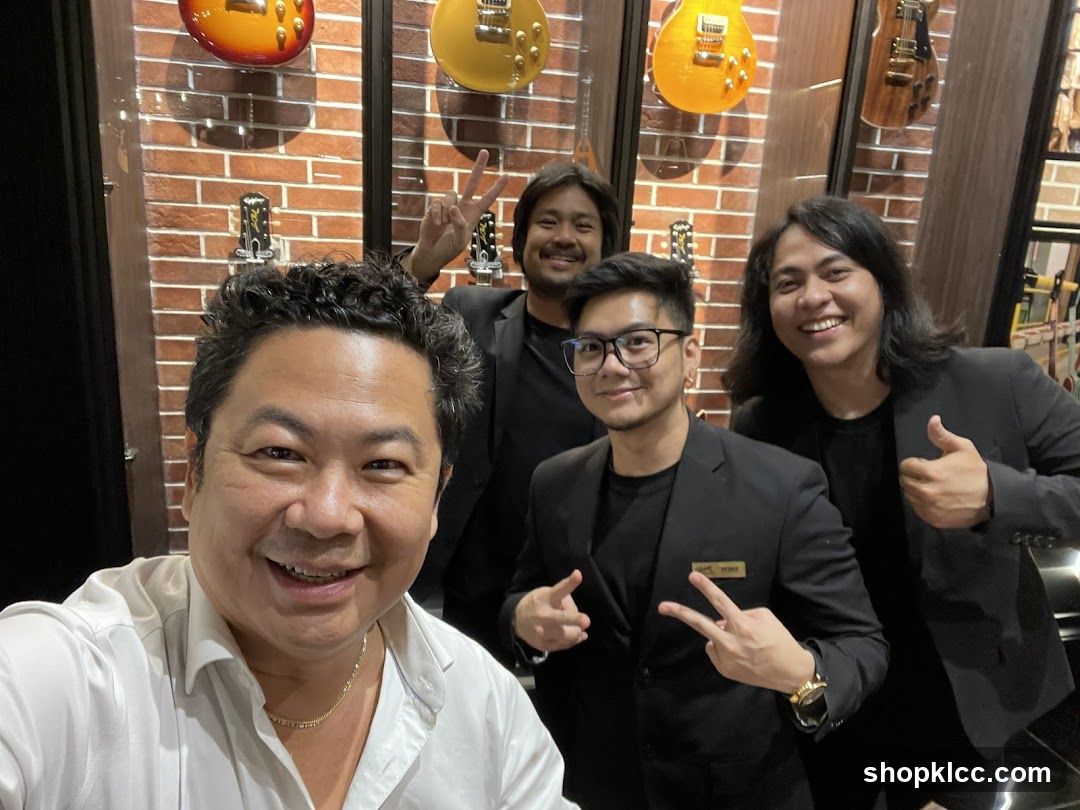 Four men posing for a photo in a guitar shop