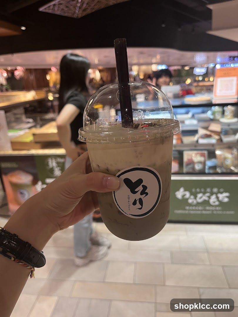 Hand holding iced coffee drink in a food court setting