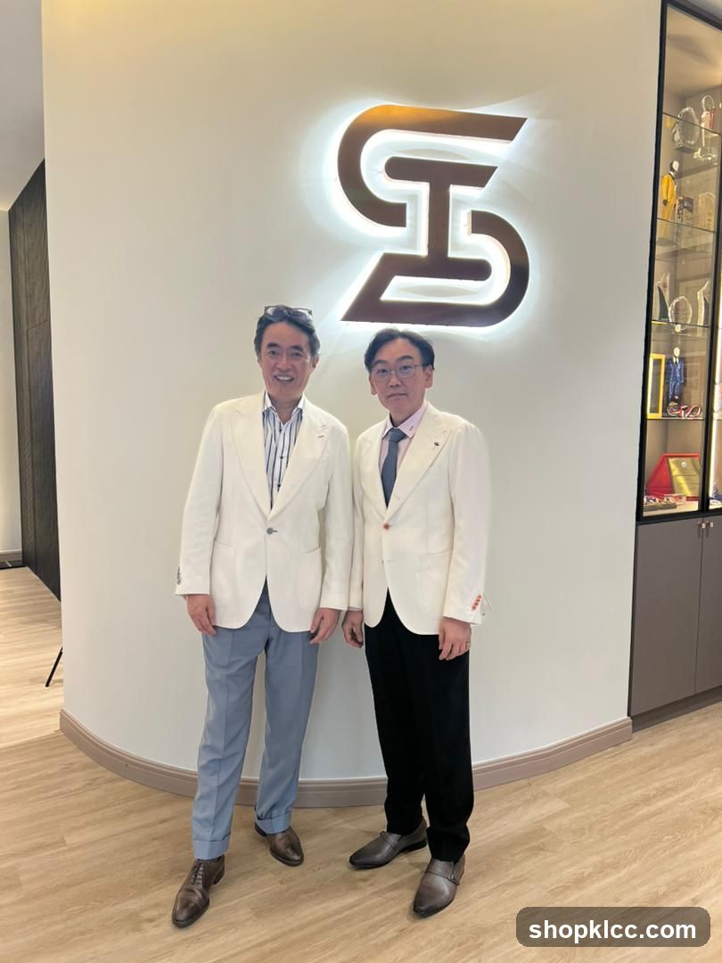 Two men in suits standing in front of a logo
