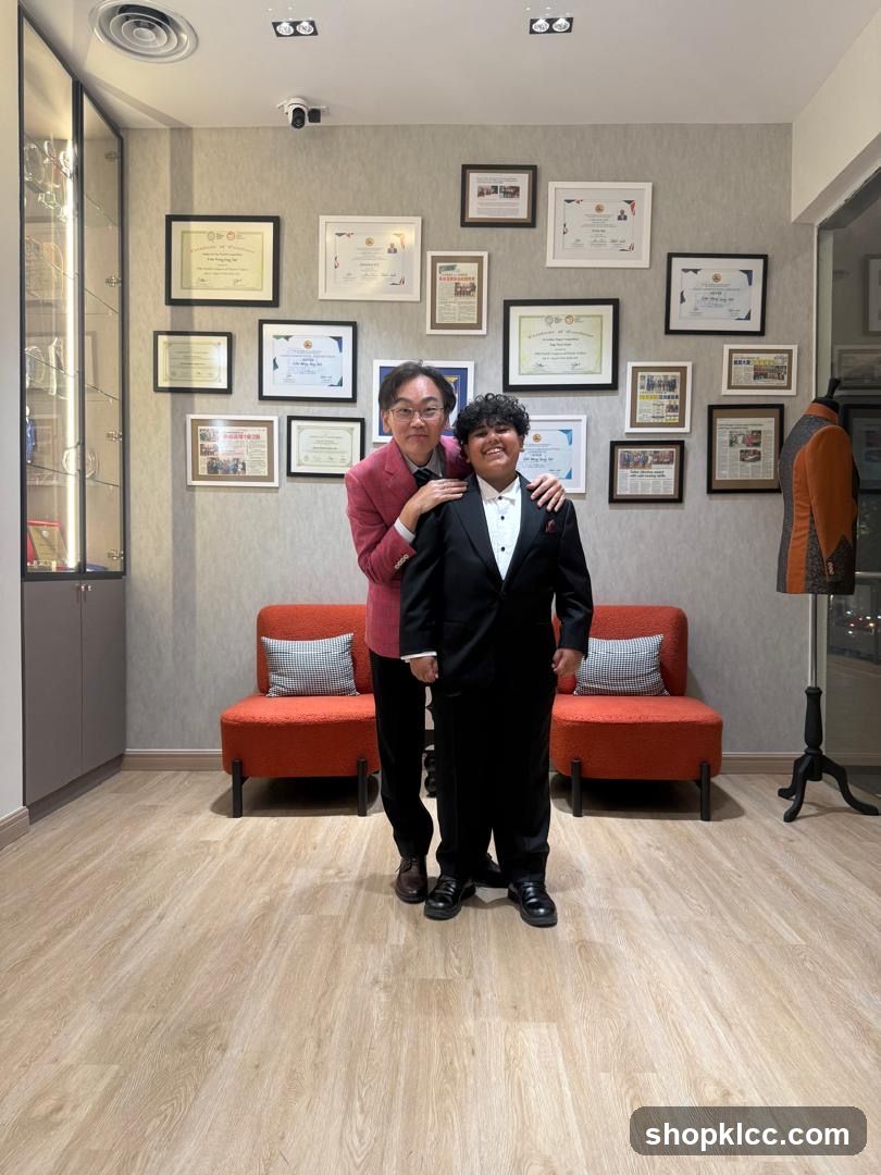 Two people in formal wear posing in a room with framed certificates on the wall.