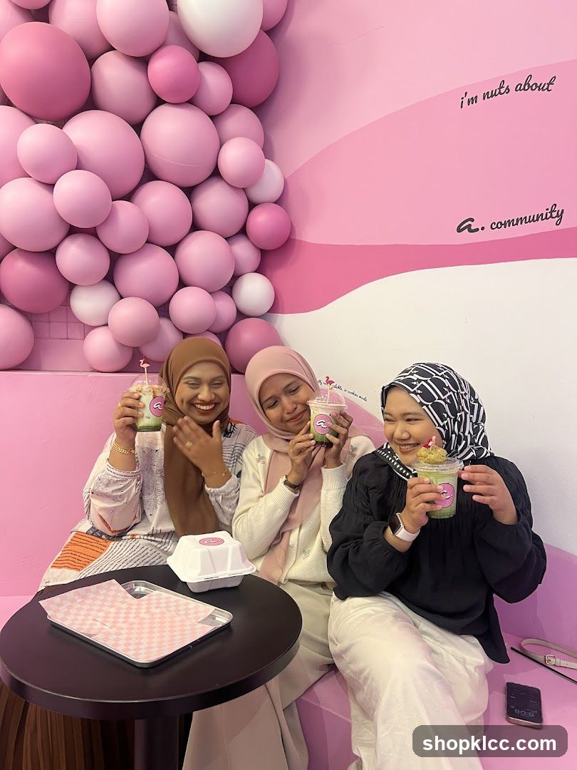 Three women enjoying drinks in a pink-themed cafe