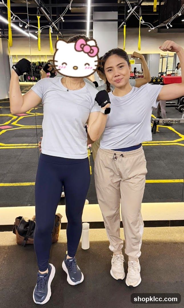 Two women flexing muscles in a gym