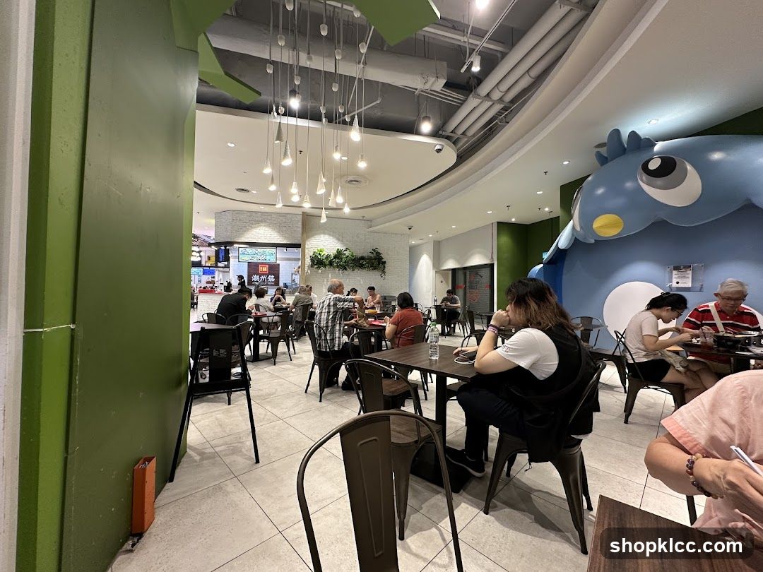 Diners in a brightly lit restaurant with a large blue cartoon character decoration