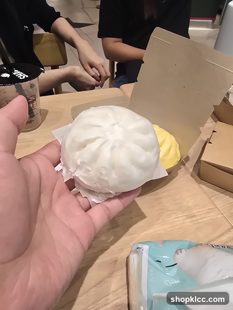 Hand holding a steamed bun at a cafe table