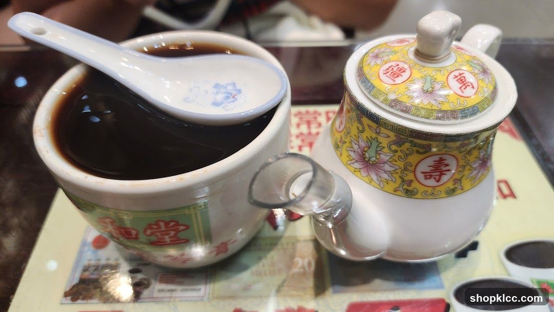 Cup of dark liquid with teapot