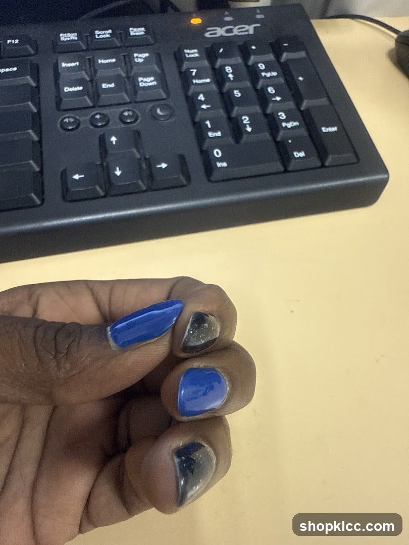 Keyboard and hand with blue and black nails