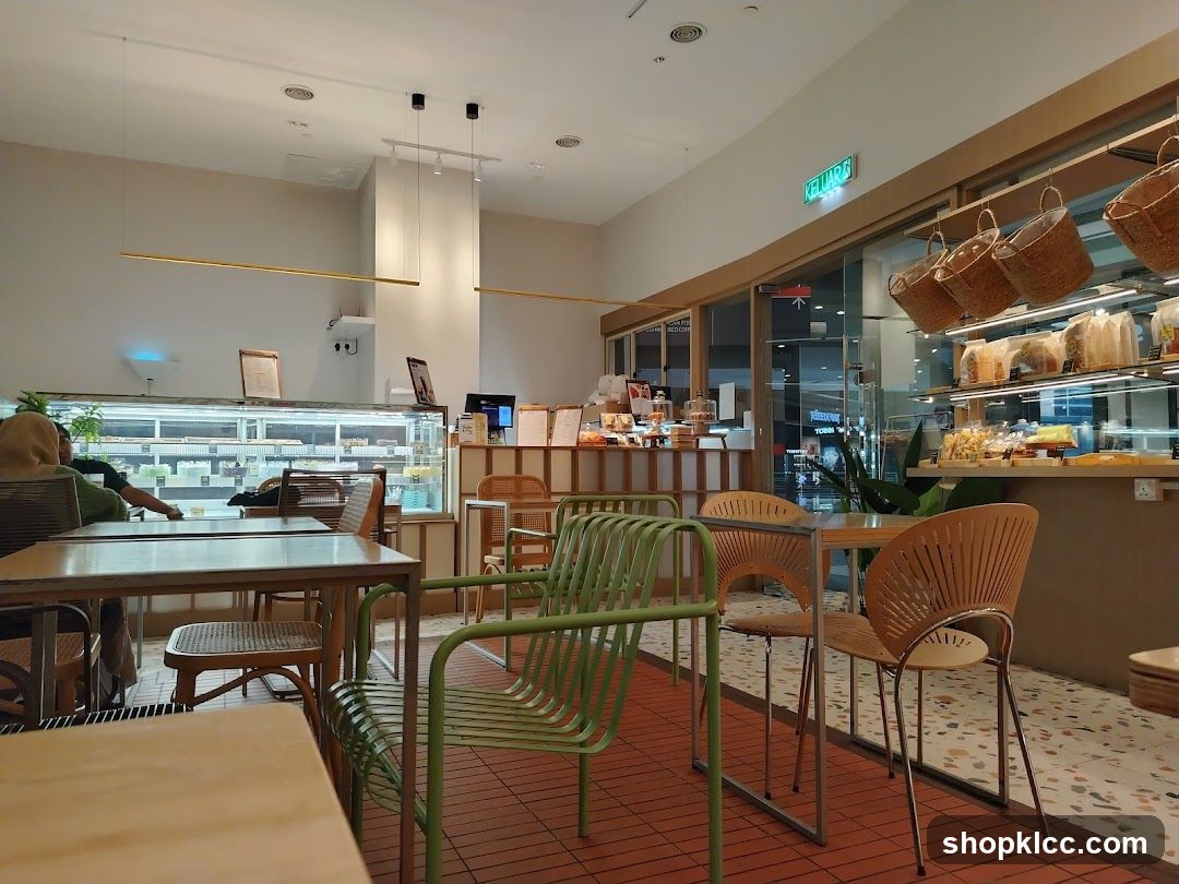 Interior of a modern cafe with display cases of pastries and seating areas.